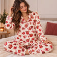 Woman in cream fleece pajamas printed with red cocoa mugs and gingerbread in a cosy bedroom