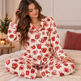 Woman in cream fleece pajamas printed with red cocoa mugs and gingerbread in a cosy bedroom