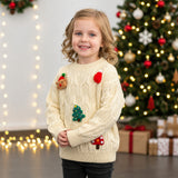 Girl in a cream cable knit Christmas sweater with reindeer, tree and hat patches