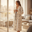 Woman by a sunny window in a long cream robe with multicoloured confetti dots