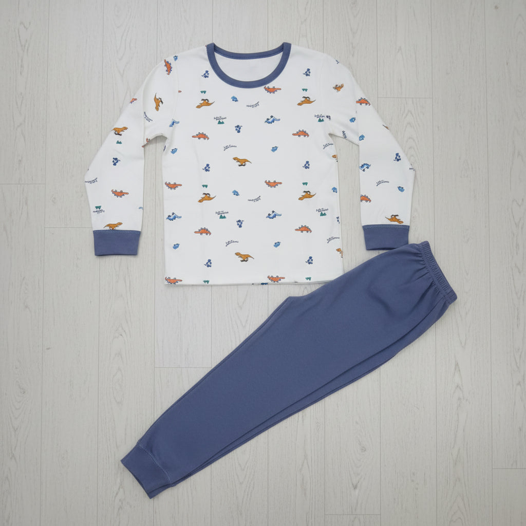 Cream dinosaur print pyjama top with slate blue joggers laid flat on a wood floor