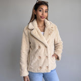 Cream faux fur coat with wide lapels and six front buttons worn over blue jeans