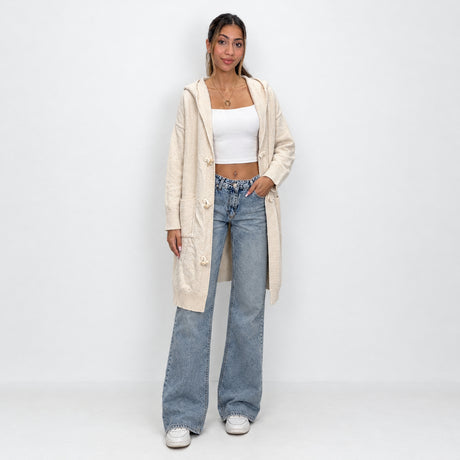 Cream long hooded cardigan with toggle fastenings and patch pockets, hand on hip