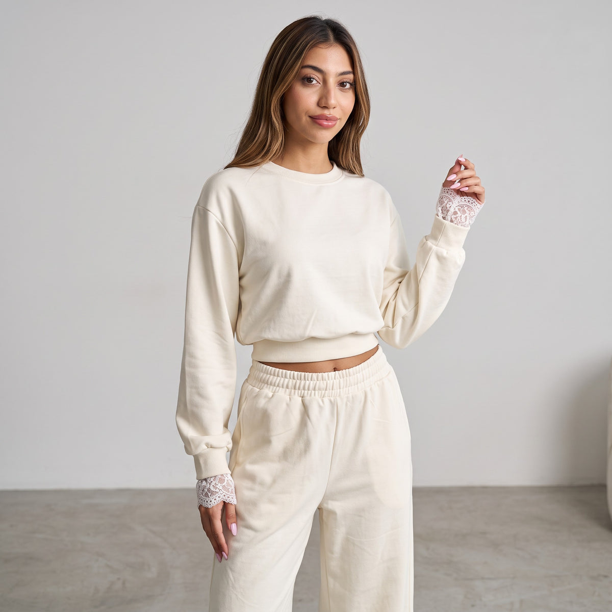 Model touching her chest, lace edging visible at the cream cuff