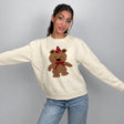 Cream knit sweater with a brown teddy bear in a red party hat and bow, arms out