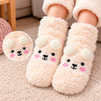 Cream fuzzy kids socks with a bear face, rosy cheeks and fluffy white pom pom ears