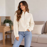 Longer view of a cream zip up knit cardigan with ribbed cuffs worn with straight leg jeans