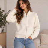 Woman in a cream ribbed knit zip up cardigan with a funnel neck, hand in her jeans pocket