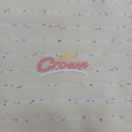 Close up of the pink script chest logo with a gold crown on cream confetti stripe pyjama fabric