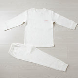 Cream speckled kids sweatshirt pyjama set laid flat on a wood floor, crew neck top with joggers