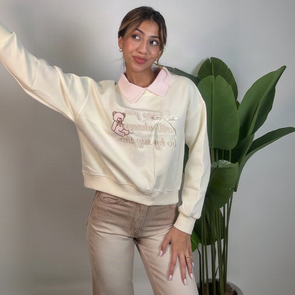 Side view of the cream sweatshirt showing the dropped shoulder and ribbed cuff