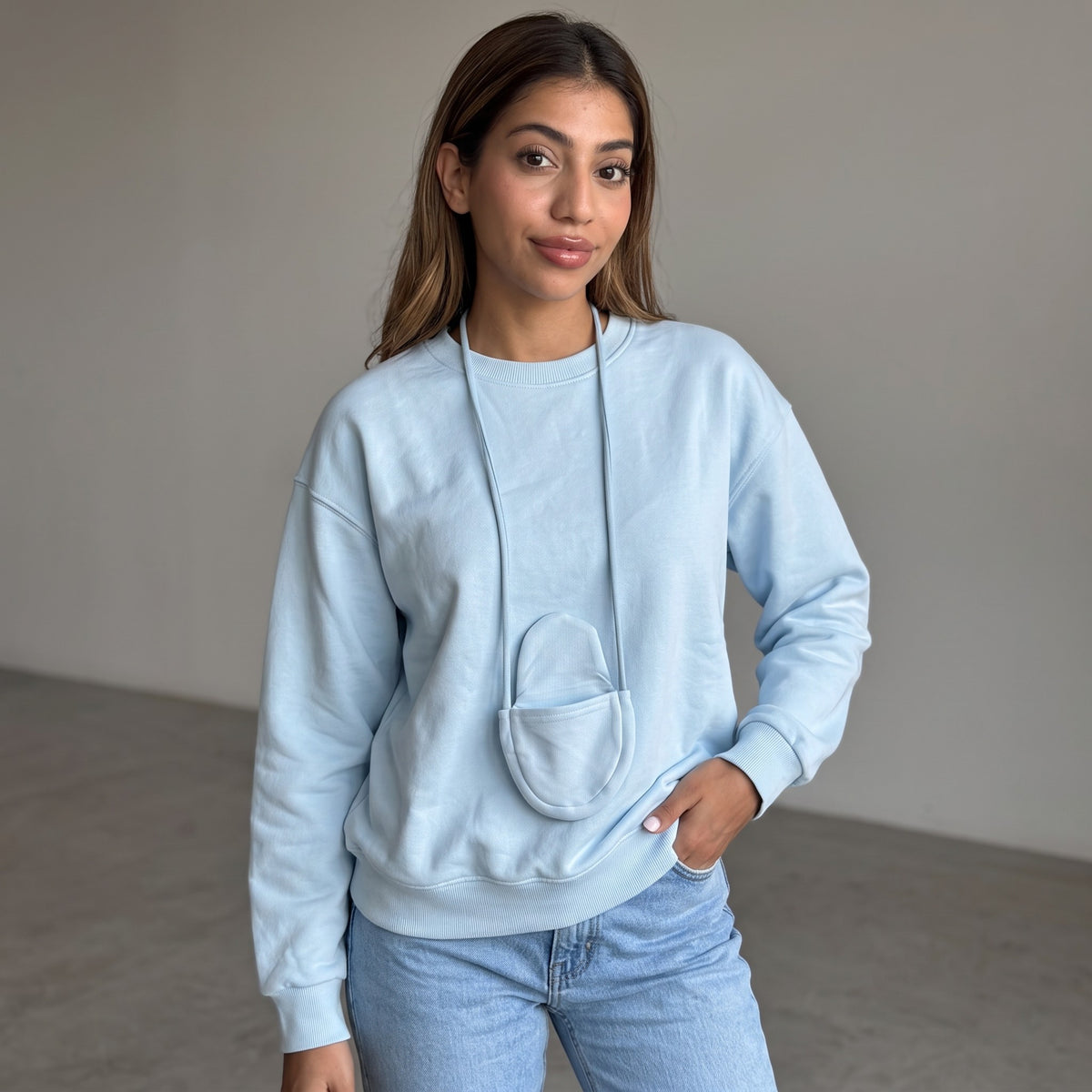 Sky blue sweatshirt with the mini pouch hanging at the chest, worn against a plain wall