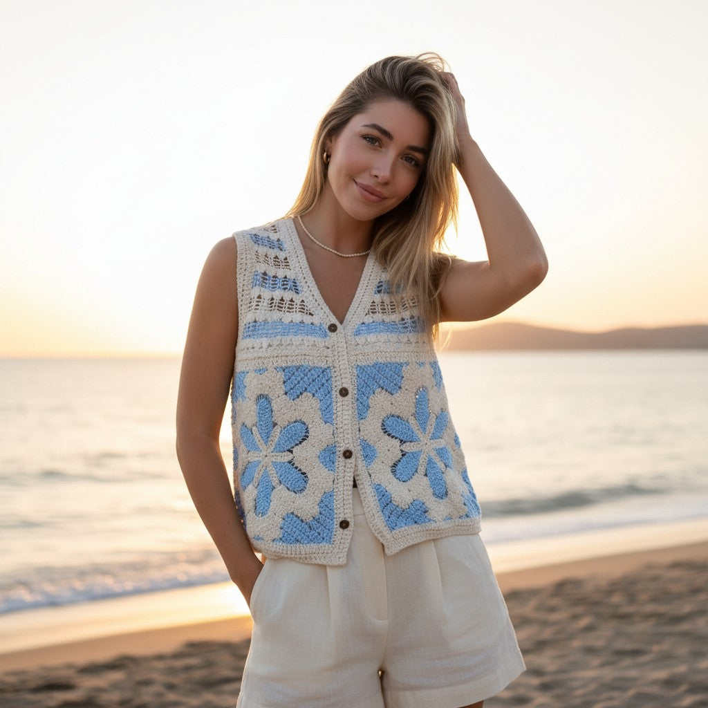 Woman wearing a blue and white patterned vest on a beach at sunset