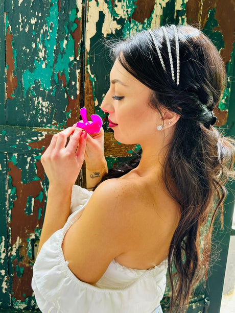 Woman with styled hair wearing a crown accessory against a textured wall
