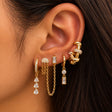 Ear styled with gold crystal teardrop hoop, chain drop studs, a baguette drop and a knotted gold ear cuff