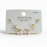 Gold tone cherry, round crystal and pearl bow stud earrings on a white display card