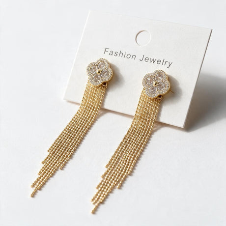 Pair of gold clover tassel earrings with fine bead chains on a white display card