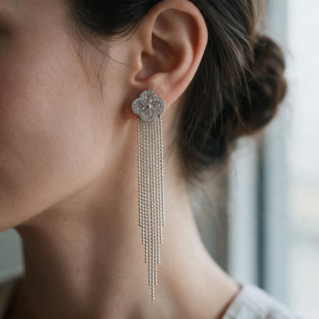 Woman with a low bun wearing a silver clover earring with a long chain fringe