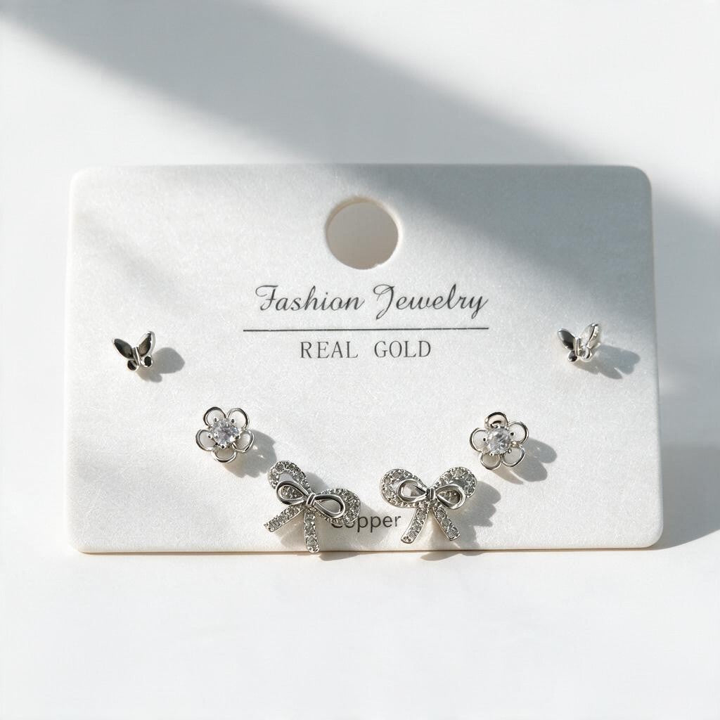 Silver tone butterfly, crystal flower and pave bow stud earrings arranged on a display card