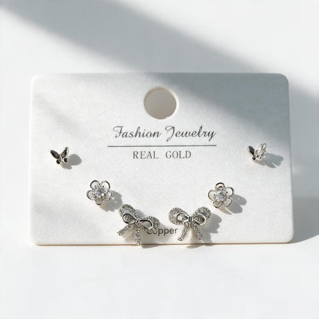 Silver tone butterfly, crystal flower and pave bow stud earrings arranged on a display card