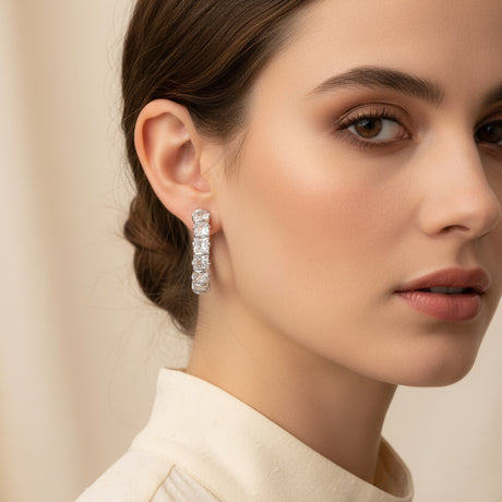 Crystal hoop earrings worn by a woman on a beige background