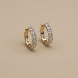 Gold crystal hoop earrings on a beige background