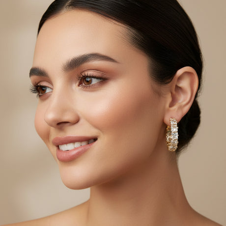 Woman wearing crystal hoop earrings on a beige bakcground