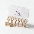 Three pairs of gold huggies with crystal quatrefoil, star and round bezel drops on a white card