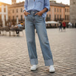 Person wearing light blue cuffed jeans and a matching shirt on a cobblestone street