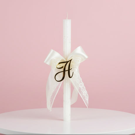White candle with a cream lace bow and gold letter H
