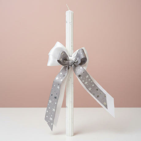 White pillar candle with a large silver star ribbon bow