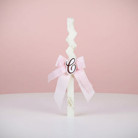 Beige zigzag candle with a light pink bow and gold letter