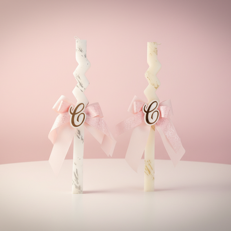 Two marble zigzag candles with pink bows and gold letter C