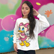 Woman wearing a white sweatshirt with a cartoon character design against a colorful background