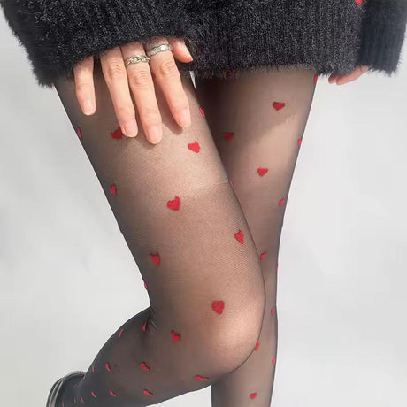 Black tights with red heart patterns worn by a person on a plain background