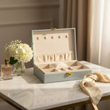 Pale blue jewelry box open to show five necklace pegs, an elastic pouch and a ring cushion