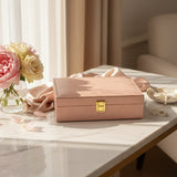 Blush pink velvet jewelry box closed with a gold rectangular flip clasp