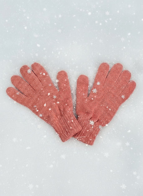 Coral pink speckled knit gloves on snow