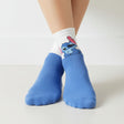 Kids white and blue ankle socks with a peeking blue Stitch print across the cuff, worn on feet
