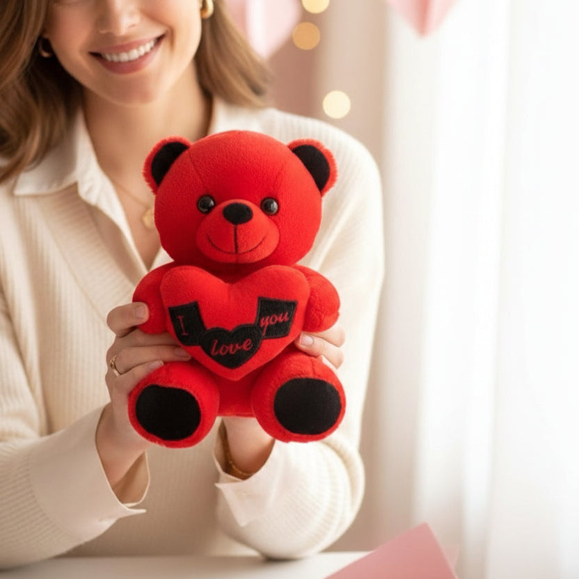 Woman holding a small bright red bear that hugs a heart reading I love you