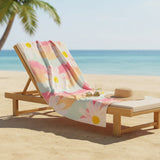 Beach chair with a colorful towel draped over it on a sandy beach with palm trees and ocean in the background.