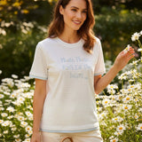 Blue striped tee with daisy lettering worn in a field of flowers