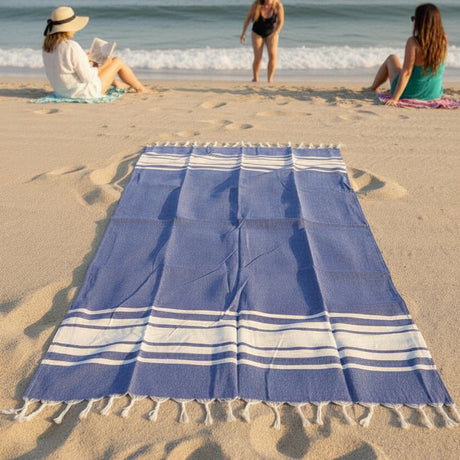 Blue beach towel on sand with people in the background