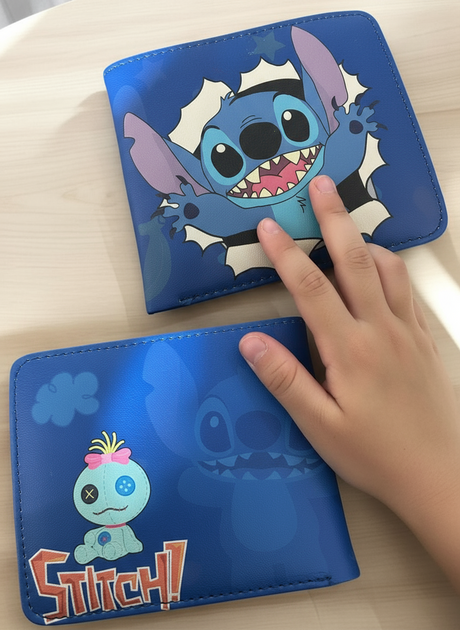 Child hand resting on two royal blue Stitch wallets showing the front and back prints on a table