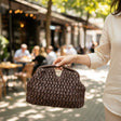 Woman holding a dark brown straw clutch bag with top handles, Jack Gifts Online Lebanon