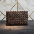 Dark brown woven leather wallet against a patterned wall