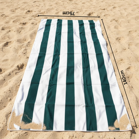 Green and white striped beach towel on sand with 75x140 cm size measurements indicated