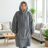 Person wearing a gray hooded blanket in a living room setting