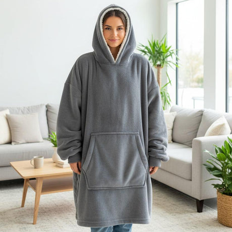Person wearing a gray hooded blanket in a living room setting