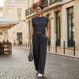 Woman in a black outfit walking on a cobbled street in an urban setting